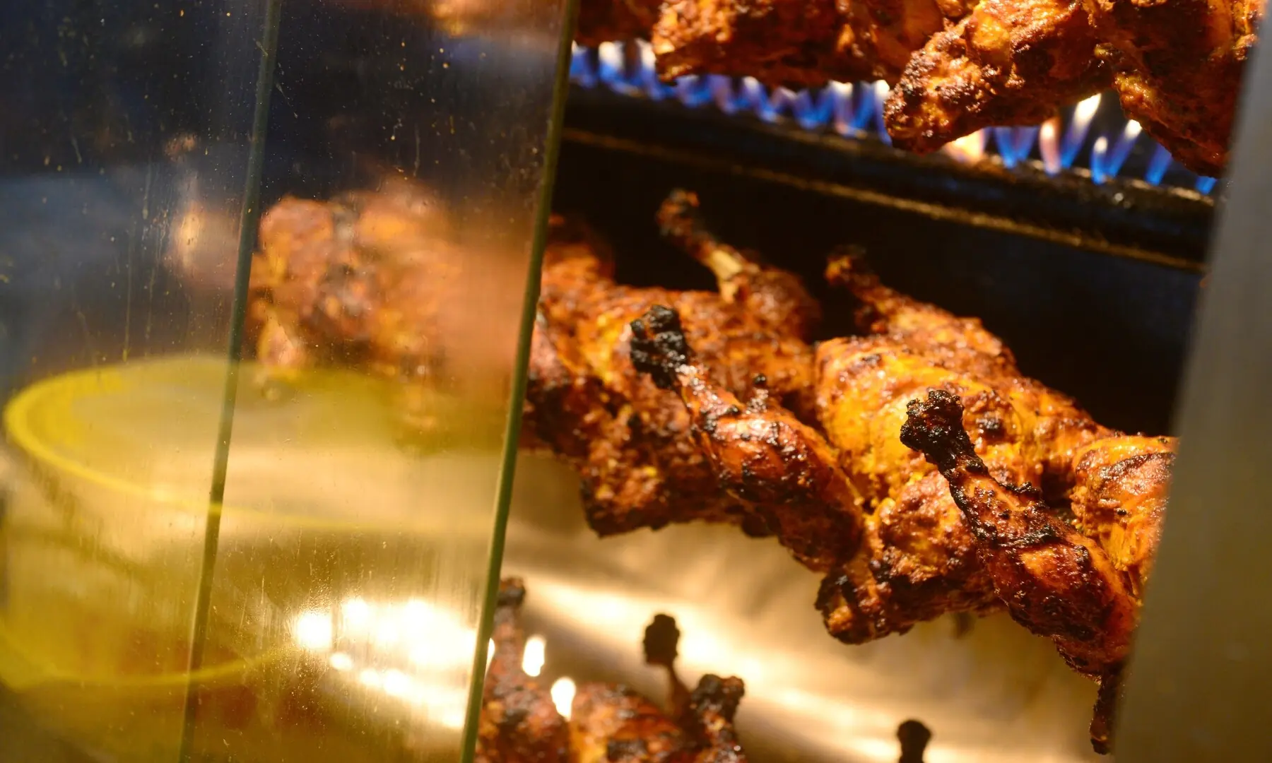 Chicken being grilled inside a glass counter at an outlet in Hussainabad, allowing customers to watch the sizzling preparation while keeping the flavours locked in. &mdash; Tahir Jamal/White Star