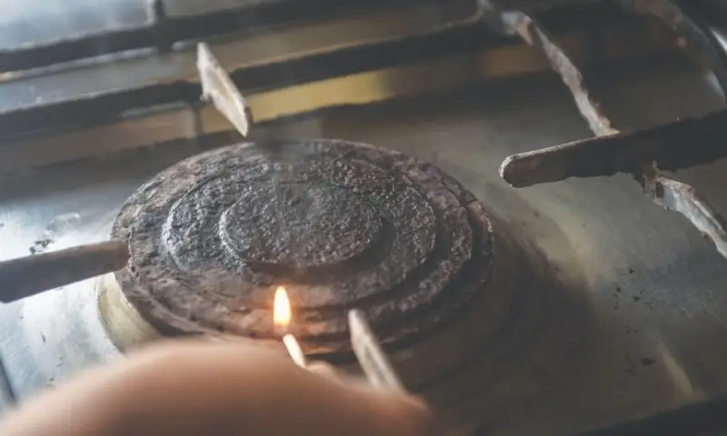 Image shows a person lighting a stove. — White Star Image shows a person lighting a stove. — White Star