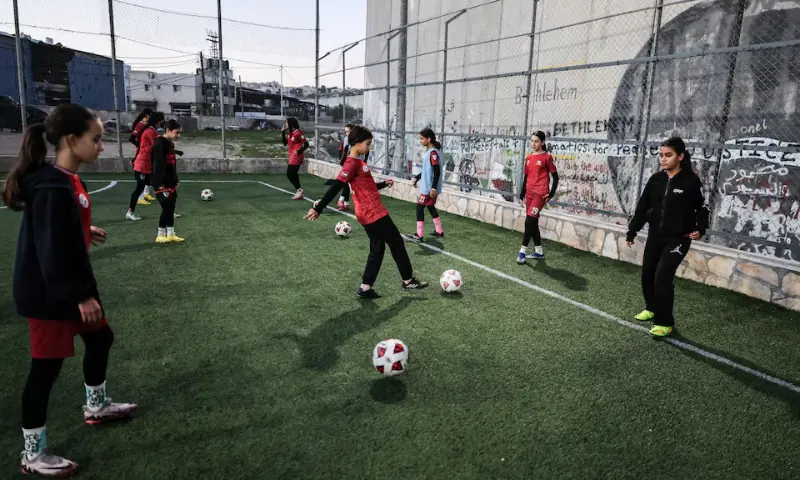 Palestinian camp team plays football in a field next to West Bank barrier separating Aida refugee camp from Jerusalem, in the Israeli-occupied city of Bethlehem on January 11, 2026. &mdash; Reuters