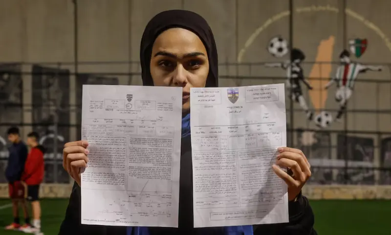 A Palestinian teen holds a demolition order of a football field, next to West Bank barrier separating Aida refugee camp from Jerusalem, in the Israeli-occupied city of Bethlehem on January 11, 2026. &mdash; Reuters