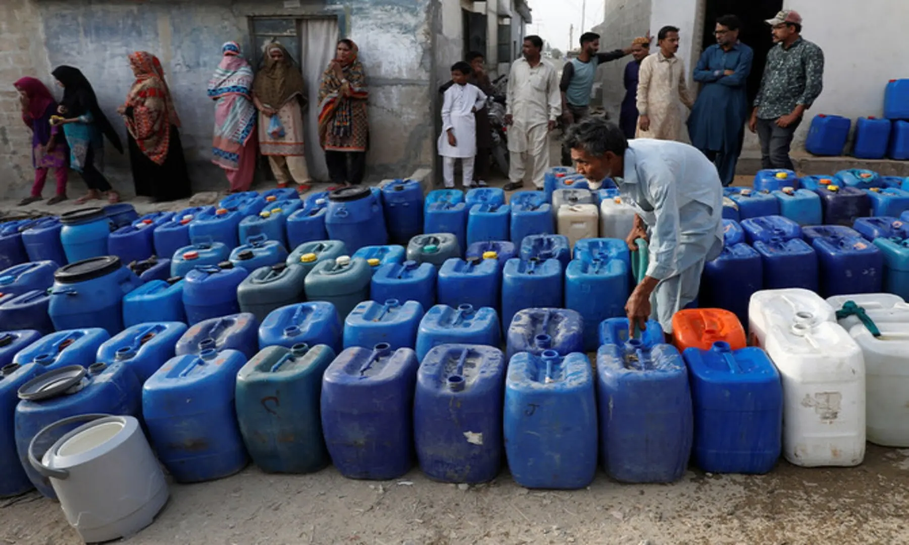 Residents gather as a worker fills containers at a free water distribution point. Used for representation only. &mdash; Reuters/ File