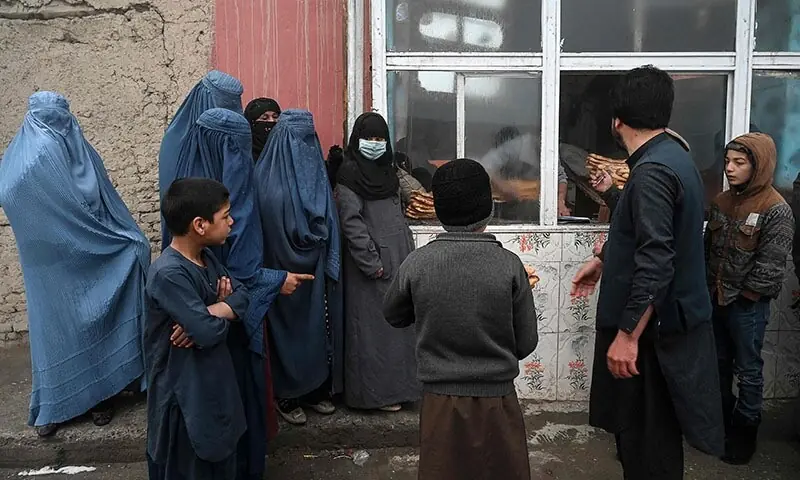 People wait to receive free bread distributed as part of the Save Afghans From Hunger campaign in front of a bakery in Kabul on January 18, 2022. &mdash; AFP/ File