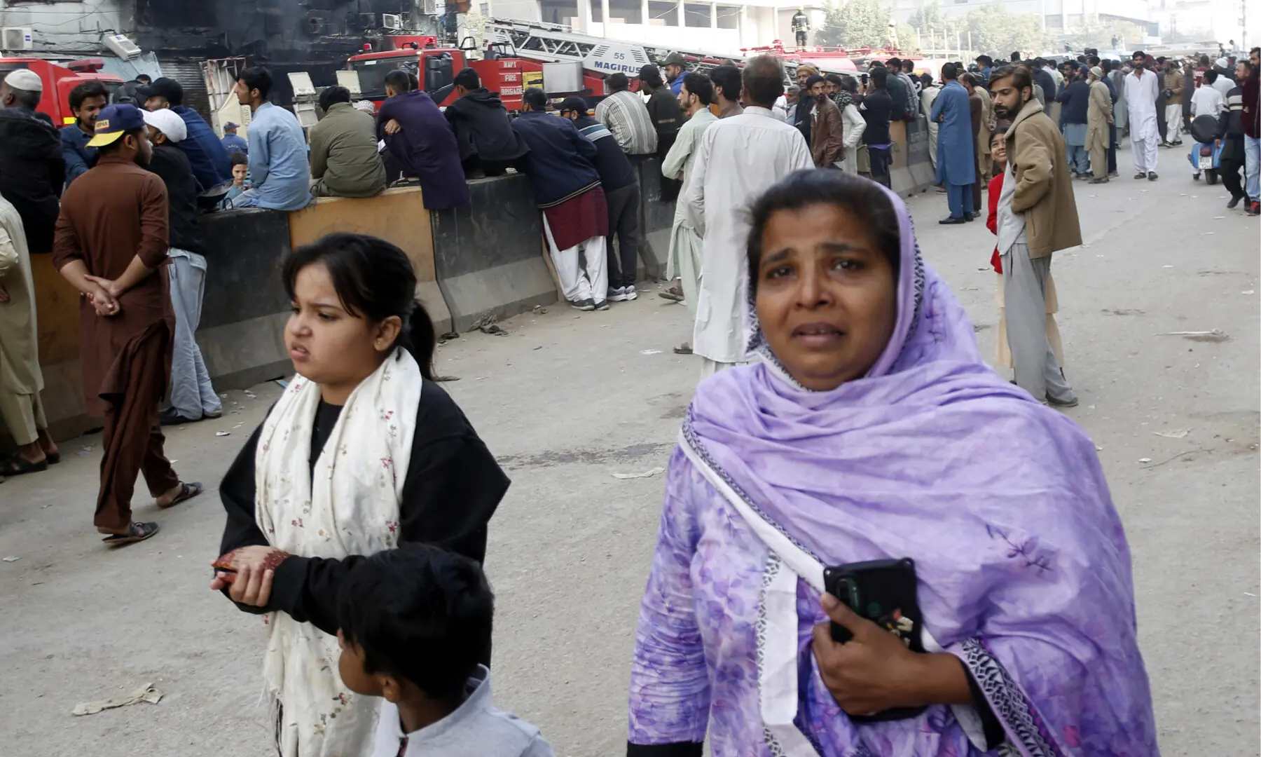 A distressed woman roams Karachi’s MA Jinnah Road, where firefighters make efforts to douse a fire at the Gul Plaza shopping mall on Jan 18, 2026. — Shakil Adil/White Star