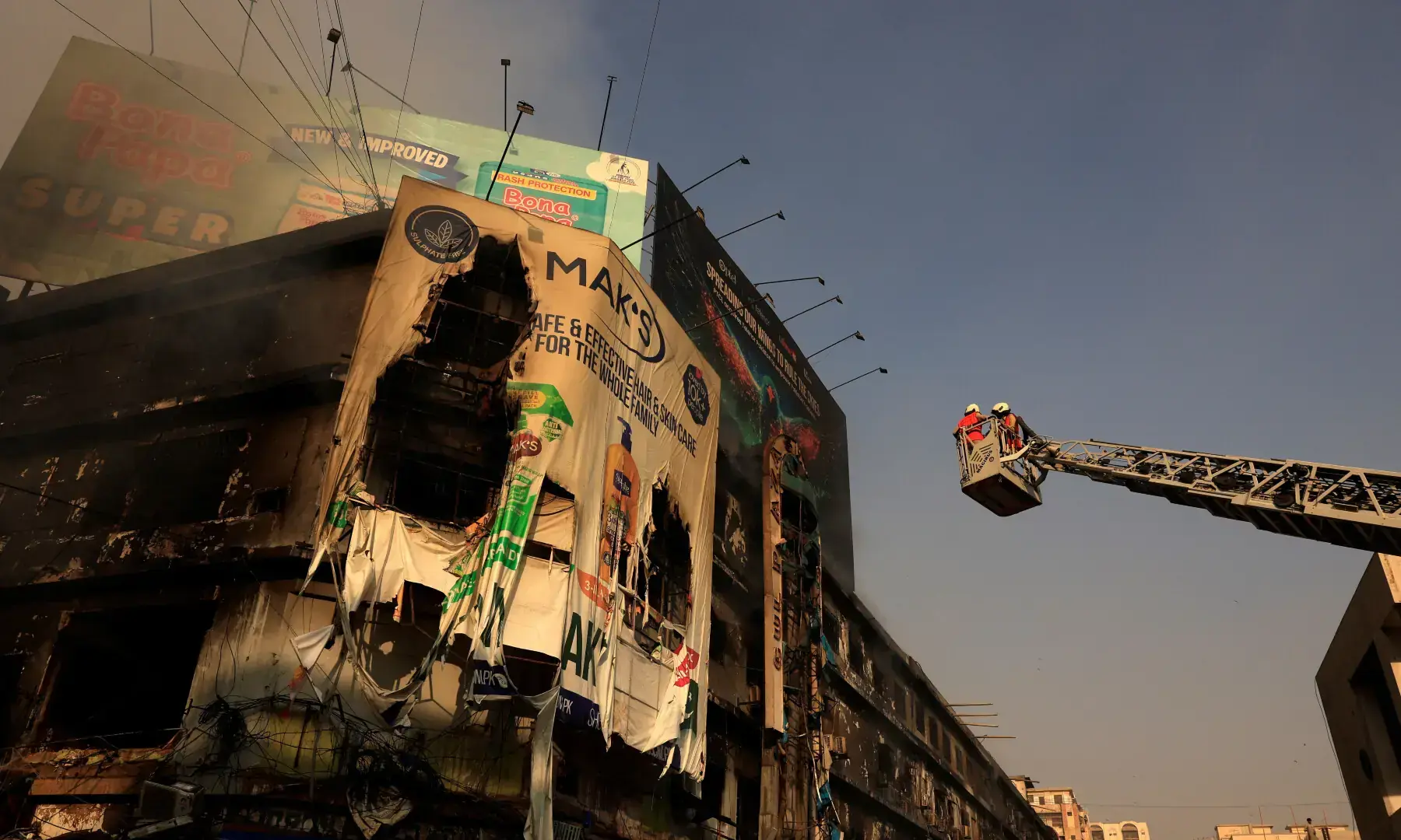 Firefighters work next to smouldering remains following a massive fire at the Gul Plaza Shopping Centre in Karachi, on Jan 19, 2026. — Reuters