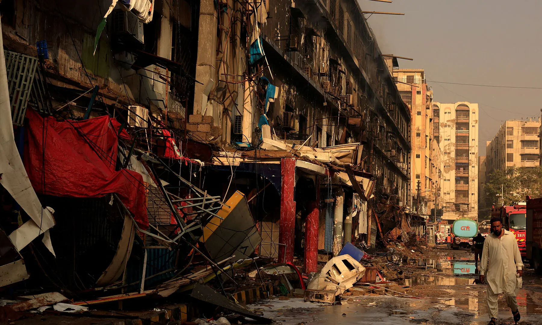  A man walks past the debris of Karachi’s Gul Plaza shopping mall on January 19 following a massive fire that broke out over the weekend. — Reuters 