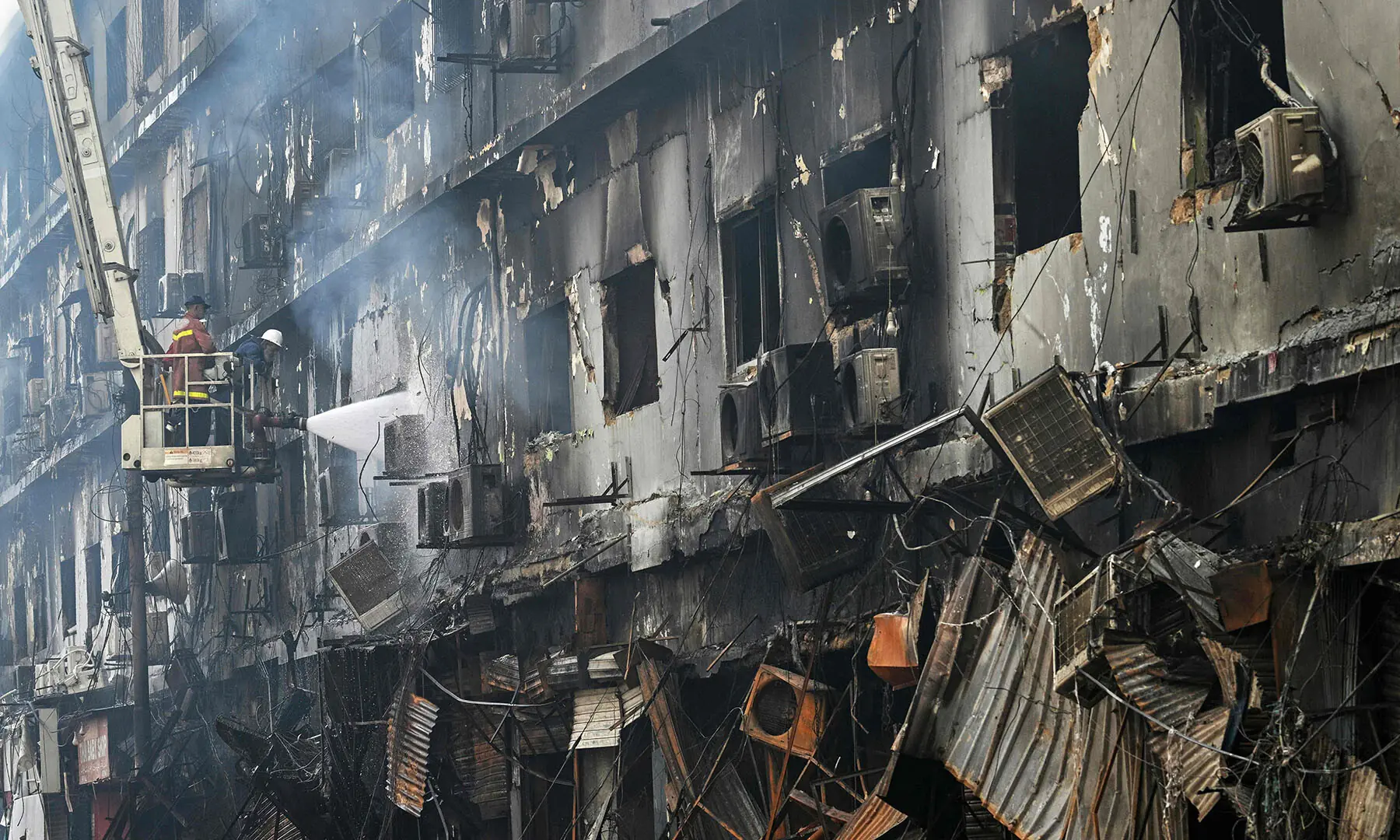 Firefighters perform a cooling operation on the burned remains of Karachi’s Gul Plaza shopping mall on January 19 after a massive fire. — AFP