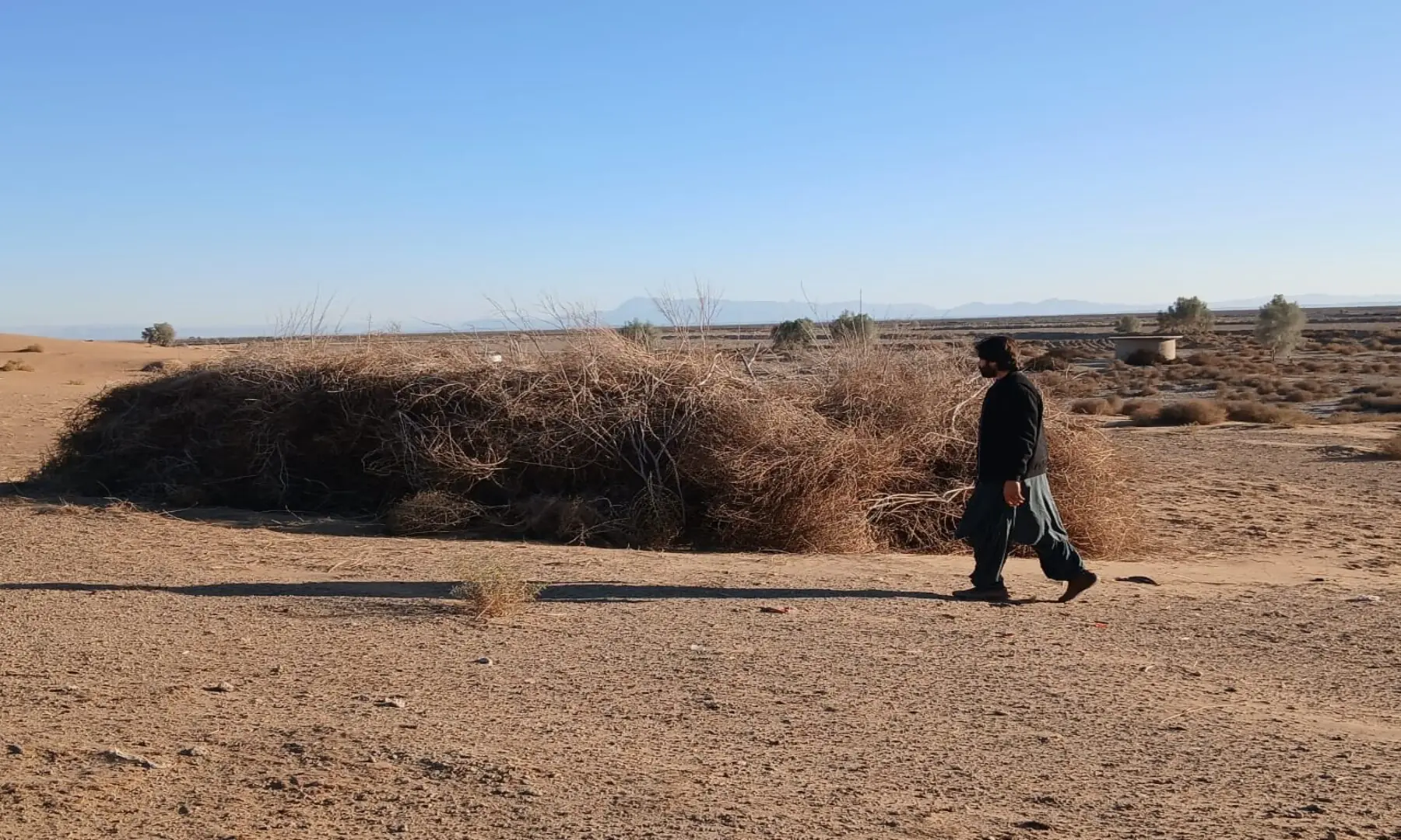 A man walks past desiccated desert scrub on a drought-stricken plain in the Daak area of Balochistan&rsquo;s Nushki,  which has been affected by repeated spells of drought since 1997. &mdash; Akbar Notezai