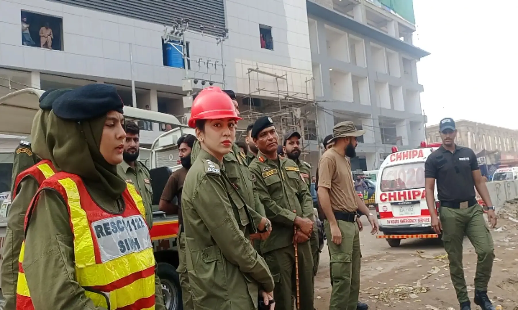  Members of the fire crew, Rescue 1122, and police stand outside Gul Plaza on Karachi&rsquo;s MA Jinnah Road. &mdash; Shazia Hasan 