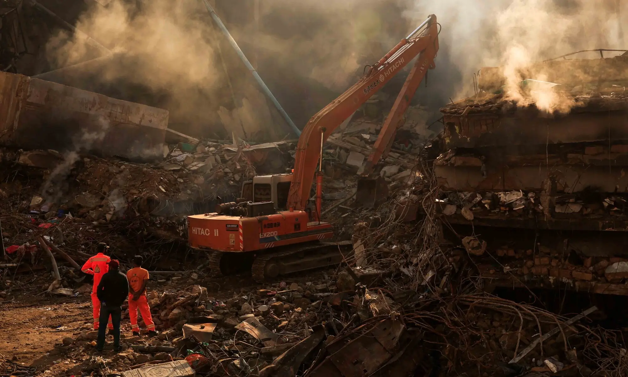 Rescue workers stand as heavy machinery is used to clear the rubble, following a massive fire that broke out at the Gul Plaza Shopping Mall, in Karachi on January 21. &mdash; Reuters