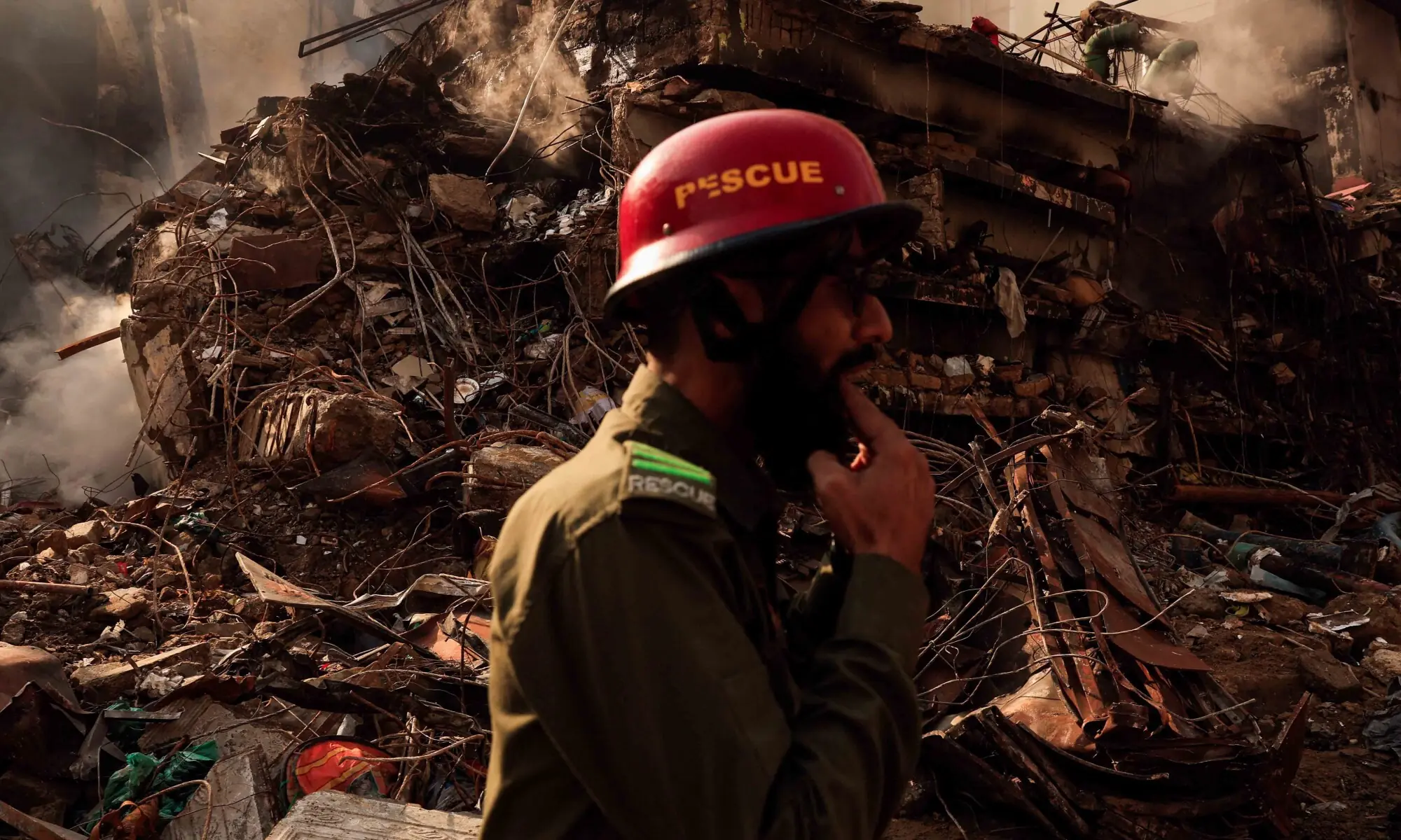 A rescue worker whistles to call his team member (not pictured) as he walks past the collapsed floors, following a massive fire that broke out at the Gul Plaza Shopping Mall, in Karachi on January 21. &mdash; Reuters