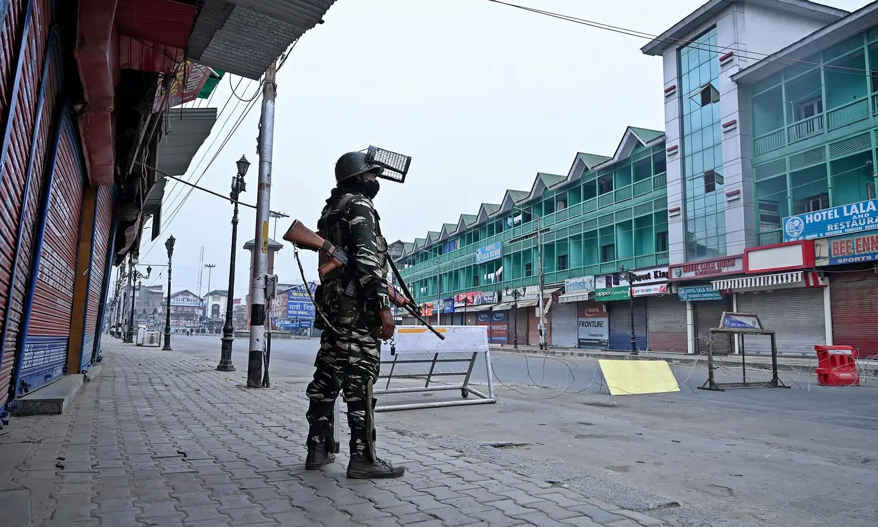 In this file photo from September 2019, a security personnel stands guard to block a road near closed shops while strict restrictions are imposed during a lockdown in Srinagar. &mdash; AFP/File