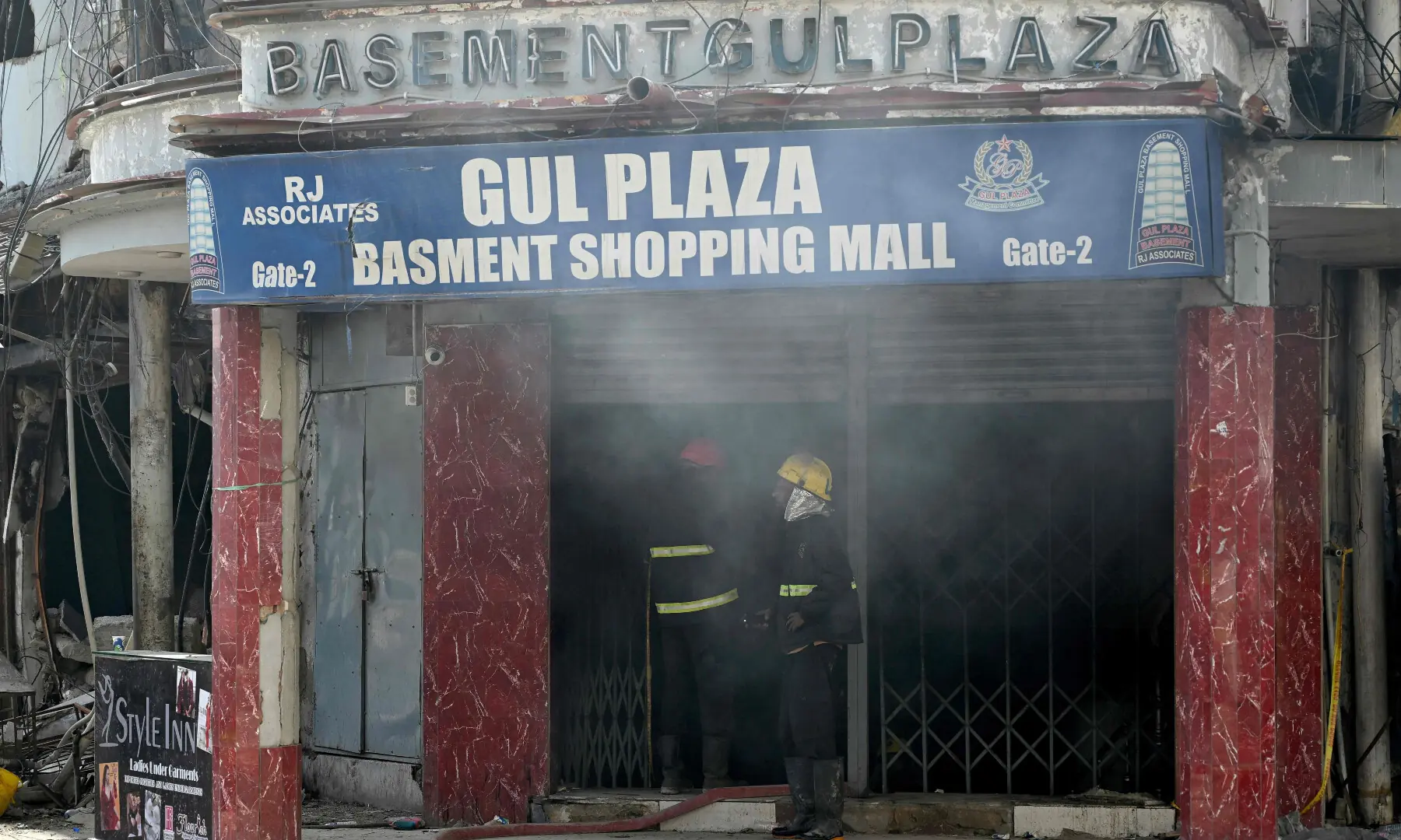 Rescue workers stand outside the charred Gul Plaza shopping mall in Karachi on Jan 23, 2026. &mdash; AFP