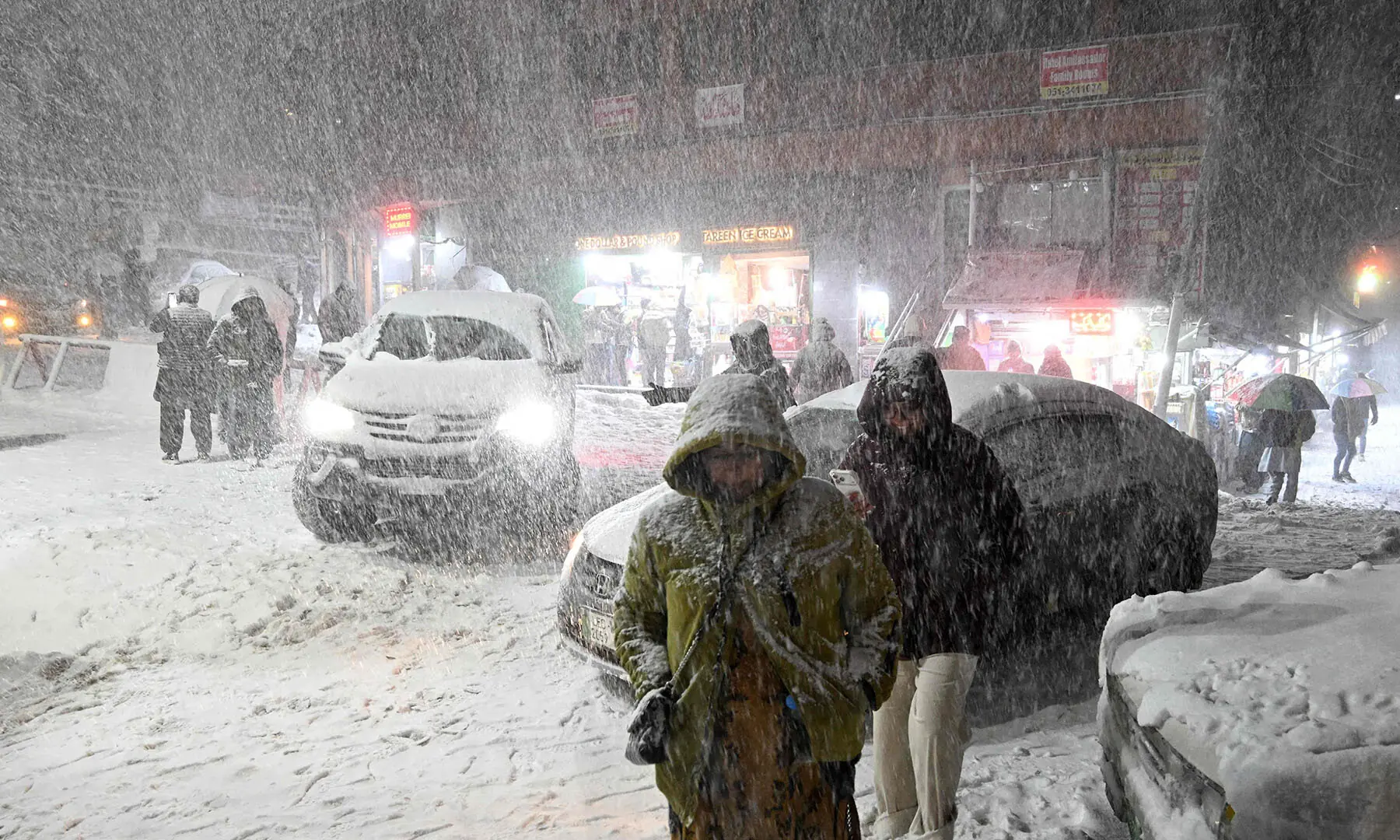 Tourists walk along a road as it snows heavily in Murree on January 23. &mdash; AFP