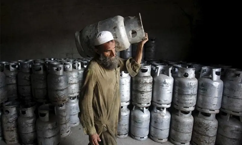 A man carries an LPG cylinder at a gas distribution centre in Peshawar. &mdash; Reuters/File