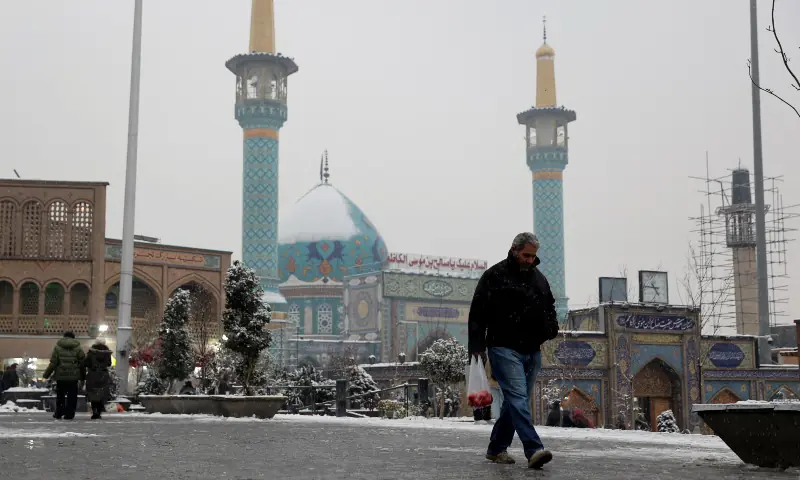 People walk during a snowfall on a street in Tehran, Iran on January 23, 2026. &mdash; Reuters