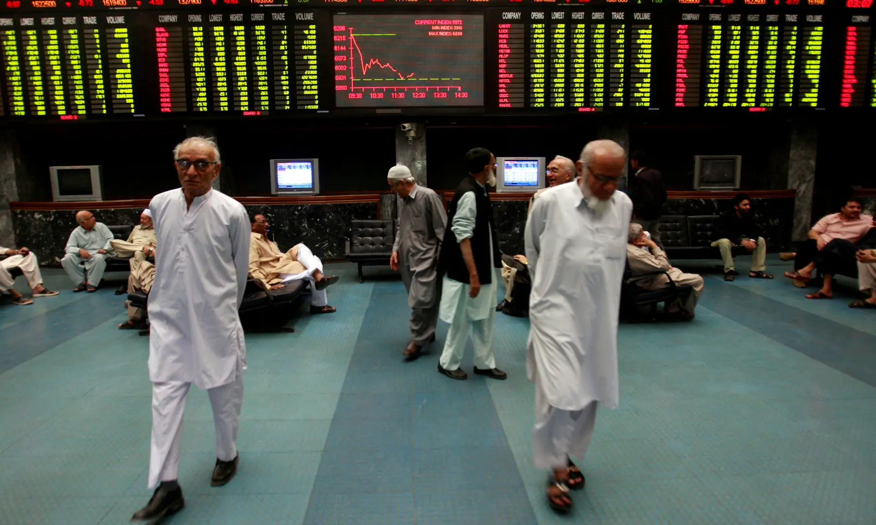 Stockbrokers walk under the digital board during a trading session inside the trading hall of the Karachi Stock Exchange, January 12, 2009 &mdash; REUTERS/file