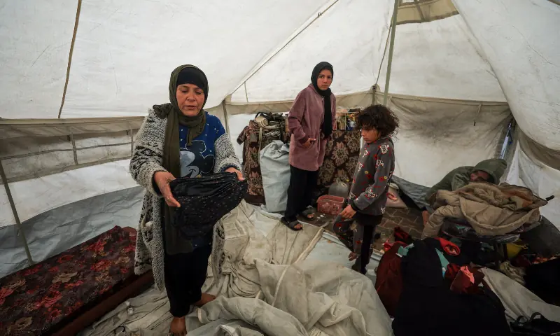 Displaced Palestinians stand inside a tent, amid a windstorm, in Gaza City on January 13, 2026. — Reuters Displaced Palestinians stand inside a tent, amid a windstorm, in Gaza City on January 13, 2026. — Reuters