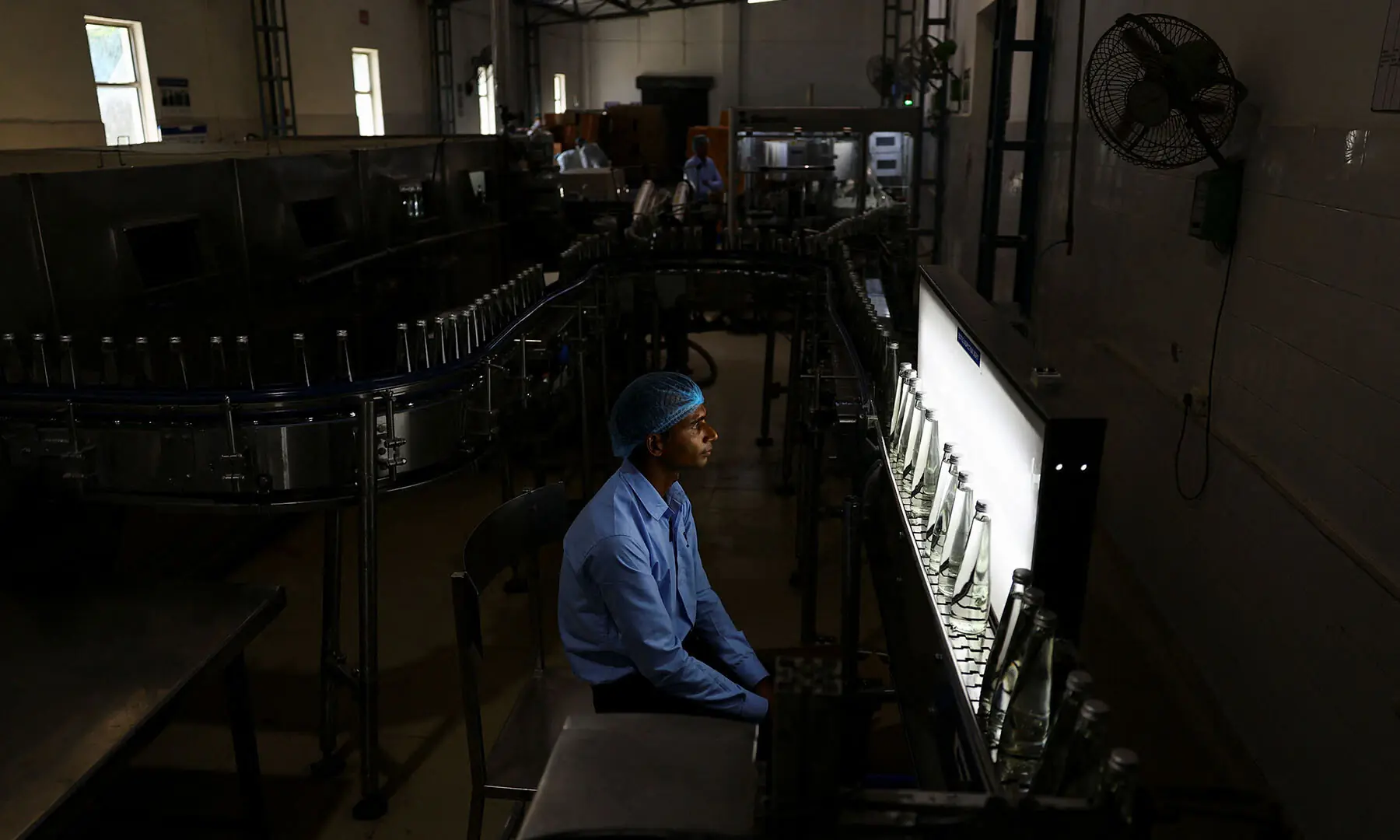 A worker inspects glass bottles filled with water against a bottle inspection light at Tata&rsquo;s Himalayan natural mineral water bottling plant in Dhaula Kuan, Himachal Pradesh, India on October 16, 2025. &mdash; Reuters