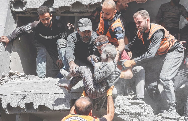 CIVIL defence personnel rescue a child from a building bombed by Israel in Gaza City. — Dawn archive