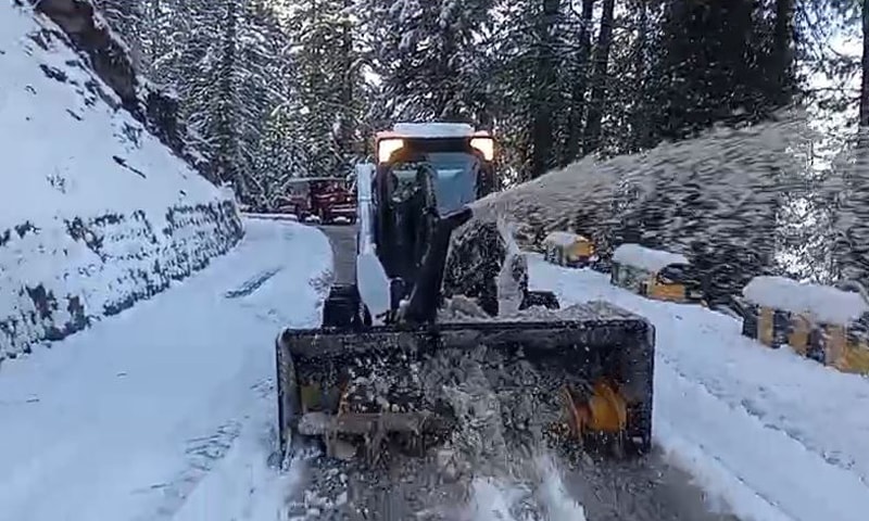 A machine clears snow from the road connecting MNJ Road with the tourist resort of Shogran in Mansehra on Thursday. &mdash; Photo by Nisar Ahmed  Khan