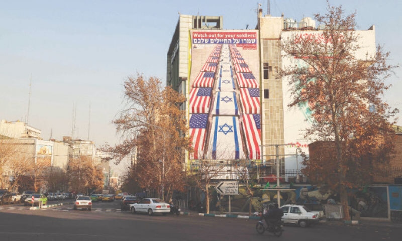 PEOPLE drive past a billboard warning the US and Israel, in Tehran.&mdash;AFP