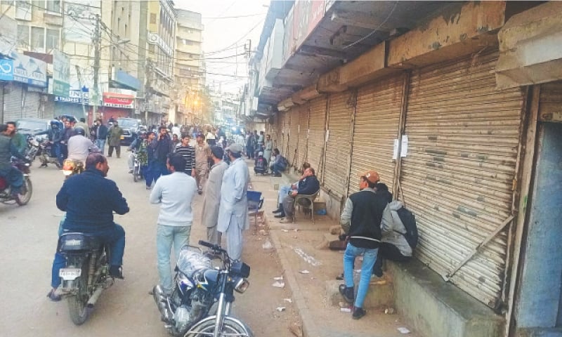 Shop owners and workers wait outside their Akbar Road outlets on Tuesday.&mdash;Shakil Adil / White Star