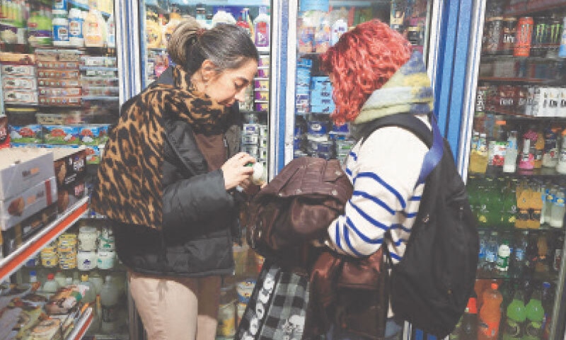 Women look at the price of milk at a Tehran store. — AFP Women look at the price of milk at a Tehran store. — AFP