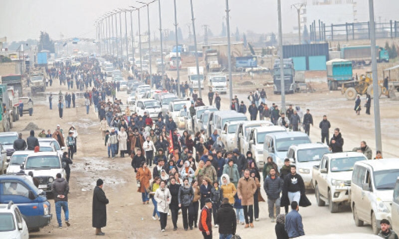 Citizens gather to welcome the arrival of vehicles transporting Kurdish fighters from Aleppo to the northeastern city of Qamishli on Sunday. &mdash; AFP