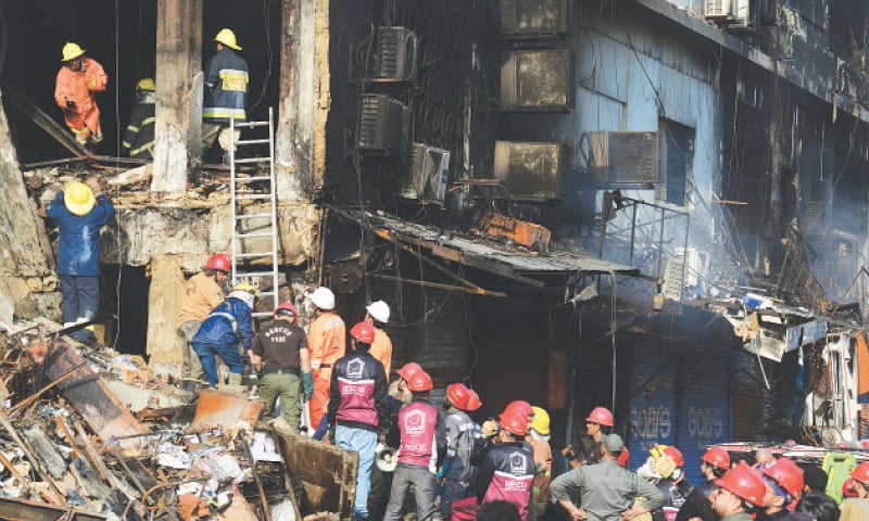 FIREFIGHTERS, rescue workers and volunteers wait on the ground as their colleagues search for the remains of those trapped inside the gutted Gul Plaza shopping mall.—Tahir Jamal / White Star FIREFIGHTERS, rescue workers and volunteers wait on the ground as their colleagues search for the remains of those trapped inside the gutted Gul Plaza shopping mall.—Tahir Jamal / White Star