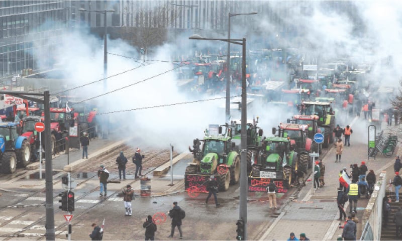 Protesters stand among parked tractors and tear gas smoke outside the European Parliament 
building in Strasbourg, France.&mdash;AFP