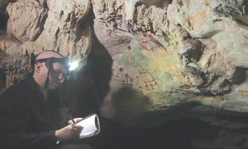 A RESEARCHER examines an ancient cave painting in a small island off Indonesia&rsquo;s  Sulawesi region.&mdash;Reuters