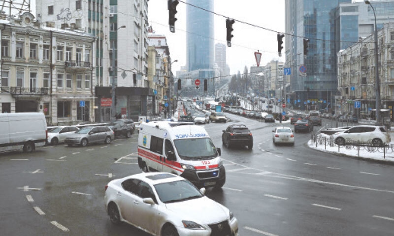 An ambulance with blue lights flashing rushes through a crossroads, amid non-functioning traffic lights, during a power outage in Kyiv.&mdash;AFP