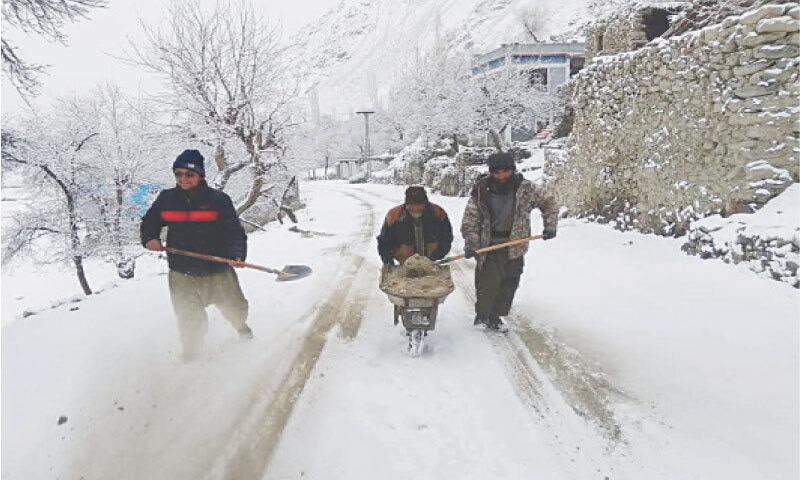 Workers throw dirt on a snow-covered road in the Ghanche district.&mdash;Photo by the writer