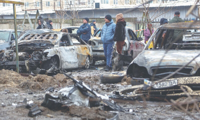 RESIDENTS stand next to burned cars near an apartment building damaged during Russian missile strikes in Zaporizhzhia.—Reuters RESIDENTS stand next to burned cars near an apartment building damaged during Russian missile strikes in Zaporizhzhia.—Reuters