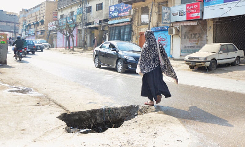 A woman walks past an open manhole on a road in Gawalmandi in Rawalpindi. — Online A woman walks past an open manhole on a road in Gawalmandi in Rawalpindi. — Online