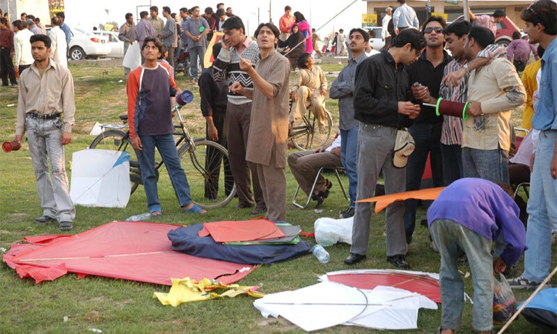 An archival image of a gigantic red kite lying on the ground while young men fly kites: the Punjab government has stipulated that wingspan of kites will not exceed four-and-a-half githi [span of hand] or dimensions of 35 inches in width and 30 inches in length. For guddas, the larger and heavier kite variants, wingspan is capped at one-and-a-half taawas or 40 inches in width and 34 inches in length | White Star