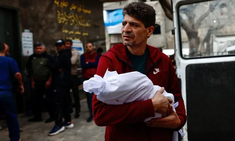 A relative of 6-month-old Mira al-Khabbaz, who was reportedly killed in an Israeli strike earlier in the day, carries her body at Al-Shifa Hospital in Gaza City on Feb 4, 2026. &mdash; AFP