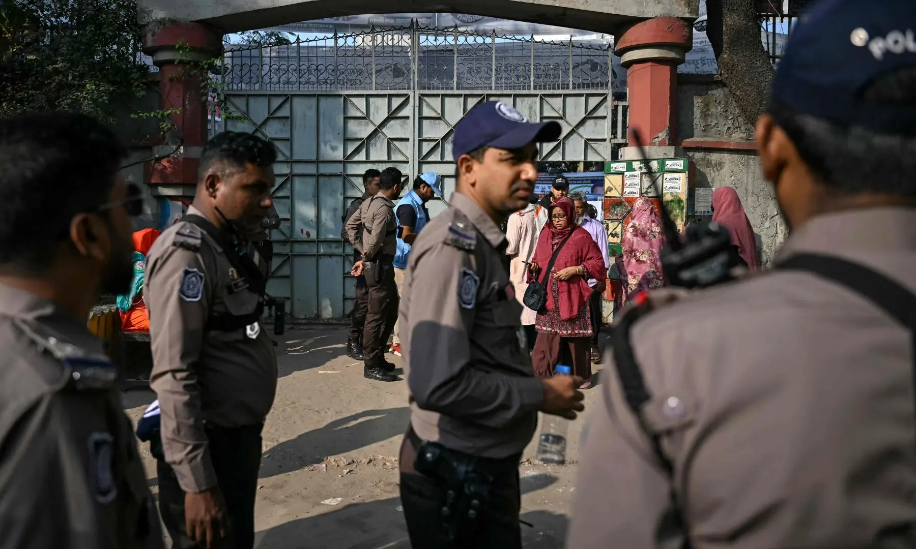Security officials look on as voters arrive at a polling station during Bangladesh&rsquo;s general election in Dhaka on February 12, 2026.  &mdash;AFP