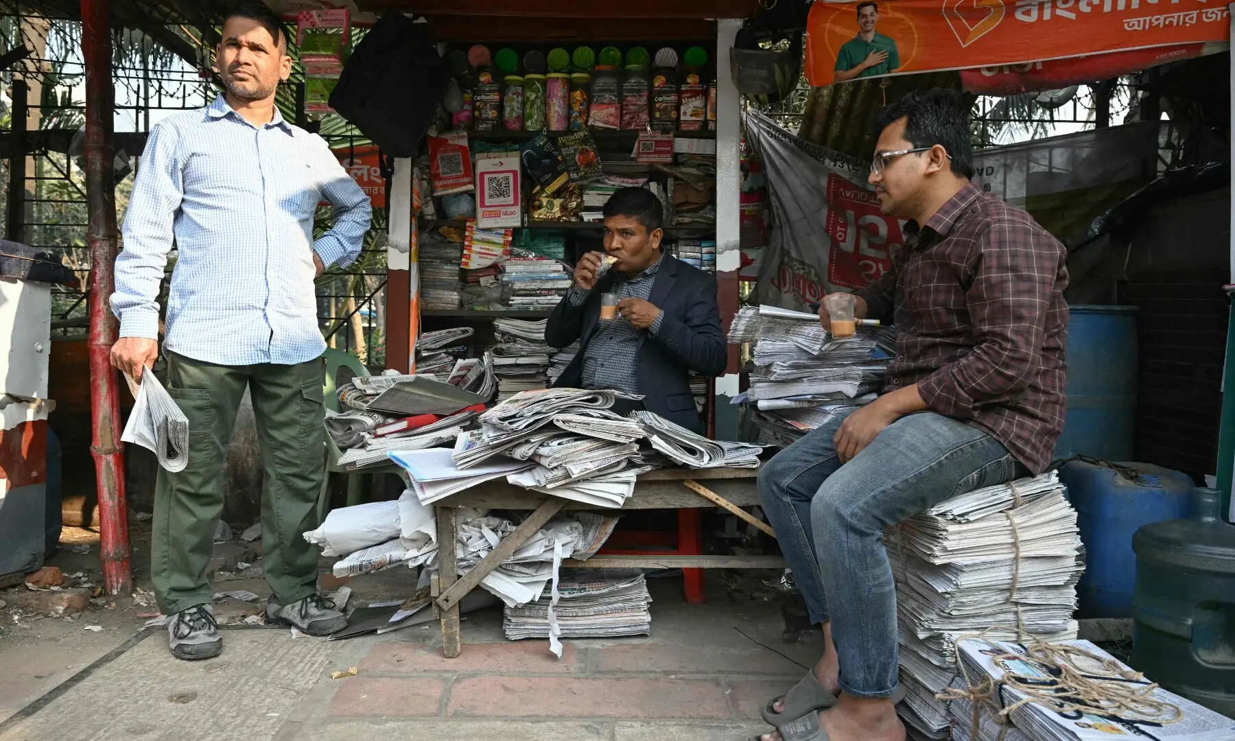 people are seen at a newspaper stall in Dhaka on February 13, 2026. &mdash;AFP