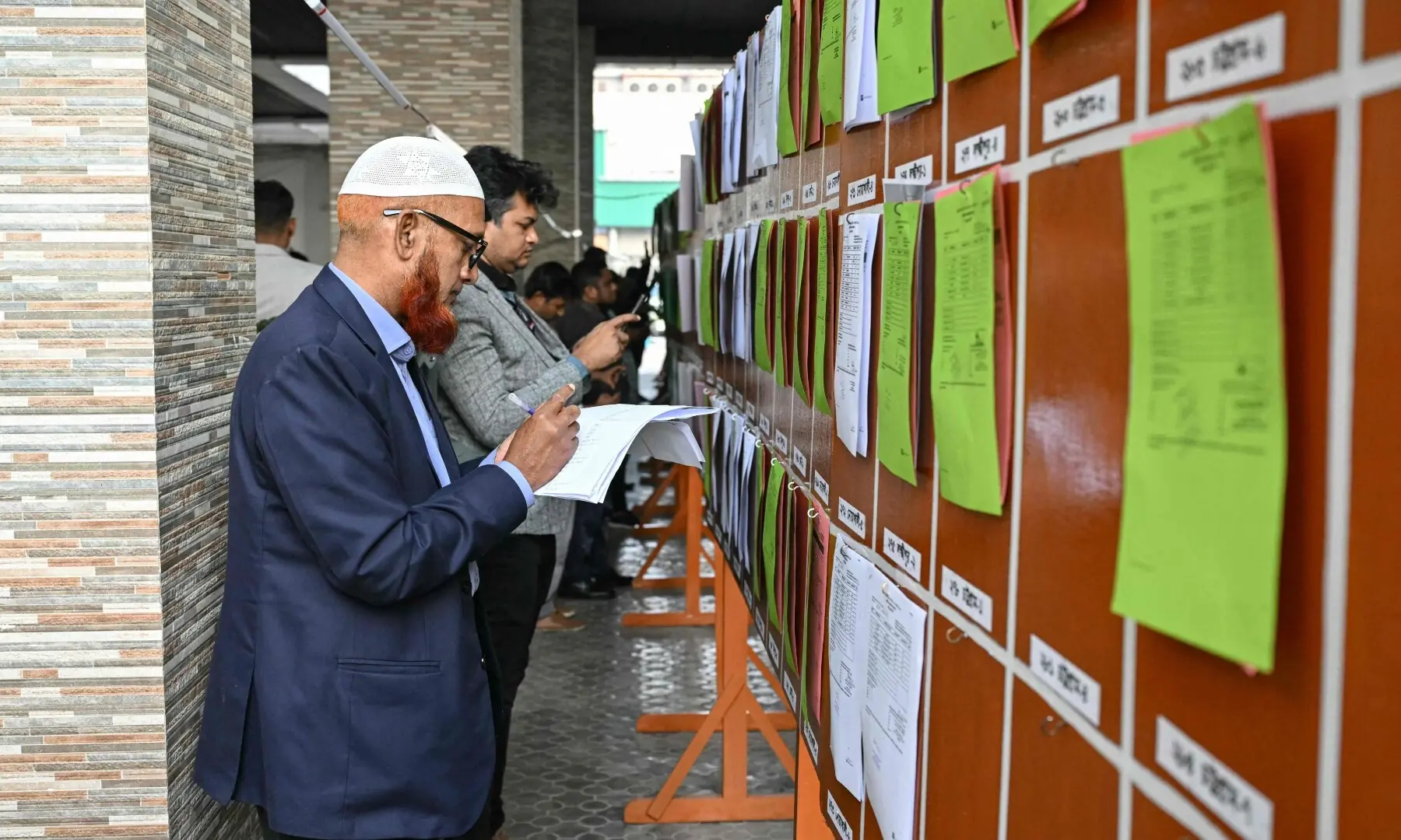 Members of the media look at documents of preliminary election results at the Election Commission office in Dhaka on February 13, 2026. &mdash;AFP