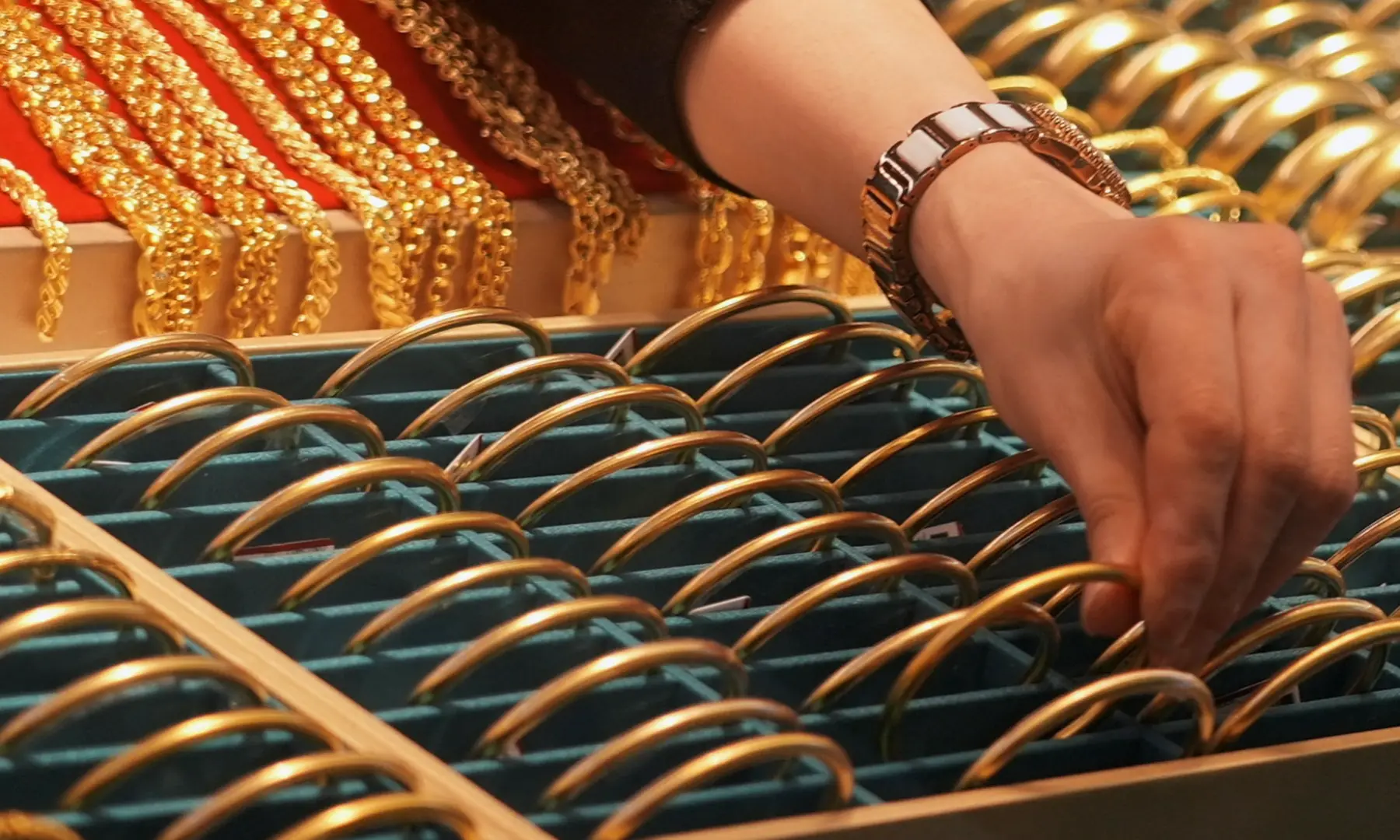 A shopkeeper adjusts gold bracelets on display at a jewellery mall in Shanghai, China &mdash; Reuters/File