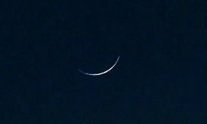 A silver crescent moon against a deep blue twilight sky.