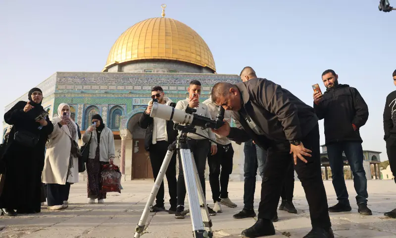 People watch as a man uses a telescope while searching for the crescent moon to mark the start of the Muslim holy fasting month of Ramadan, near the Dome of the Rock Shrine at the Al-Aqsa mosque compound, in the Old City of Jerusalem on Feb 17, 2026. &mdash; AFP