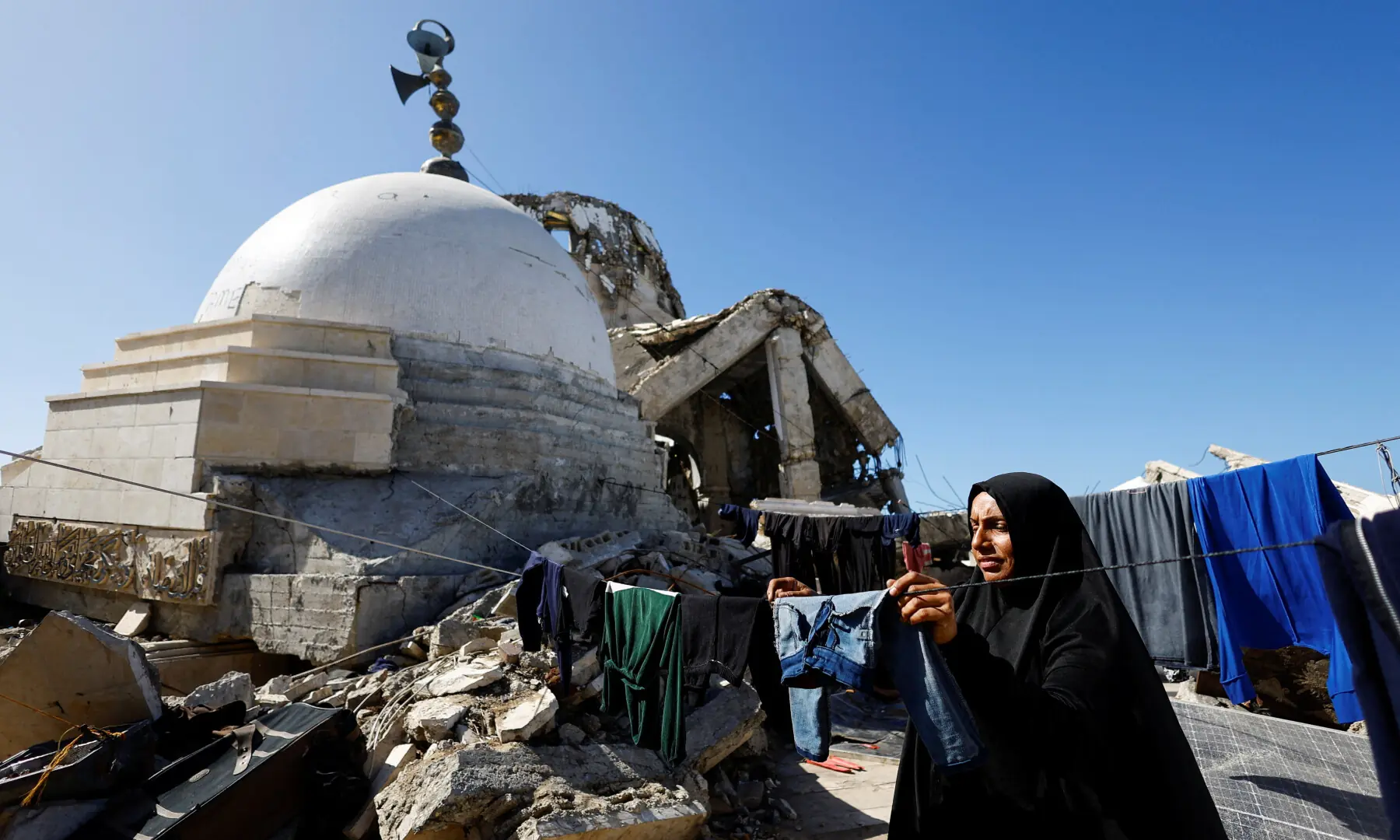 A displaced Palestinian woman hangs laundry to dry on a line at a tent camp near a mosque destroyed during the two-year Israeli offensive, in Gaza City, on Feb 11, 2026. &mdash; Reuters