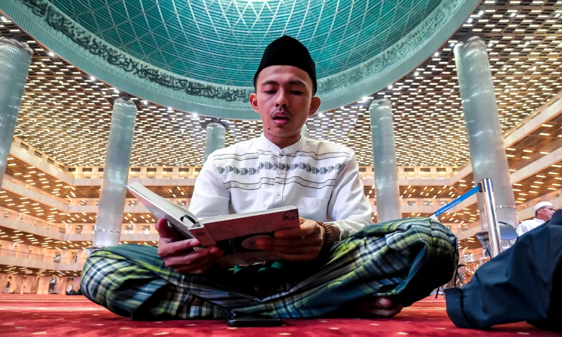 A Muslim devotee reads the Quran while waiting to break fast at Istiqlal Mosque in Jakarta on February 19, 2026. &mdash; Bay Ismoyo / AFP