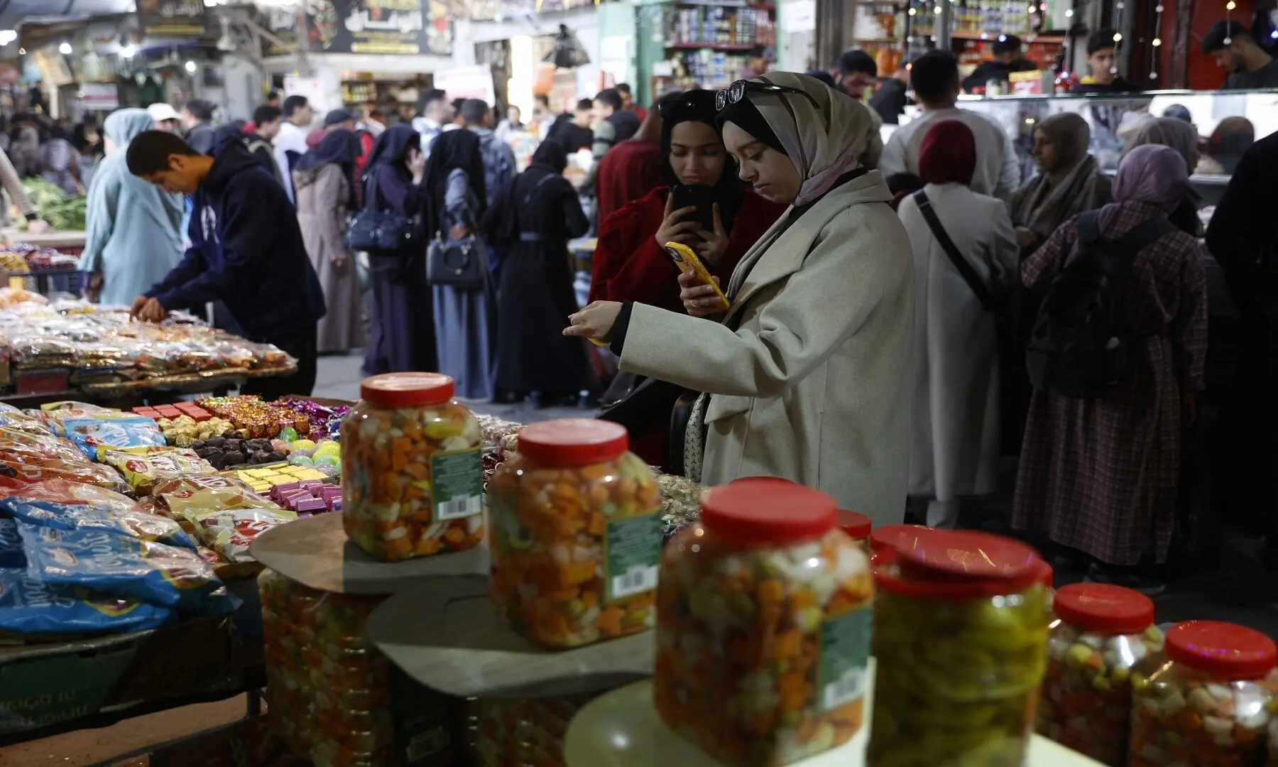 Palestinian women stand in front of a stall selling sweets in Gaza City&rsquo;s Zawiya market on February 18, 2026, on the first days of the holy fasting month of Ramazan. &mdash; Omar Al-Qattaa/ AFP