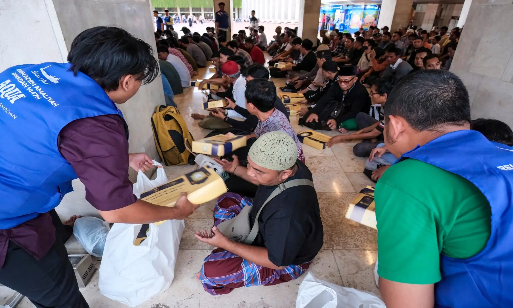 Staff members distribute iftar meals to Muslim devotees ahead of breaking their fast at Istiqlal Mosque in Jakarta on February 19, 2026. &mdash; Bay Ismoyo/ AFP
