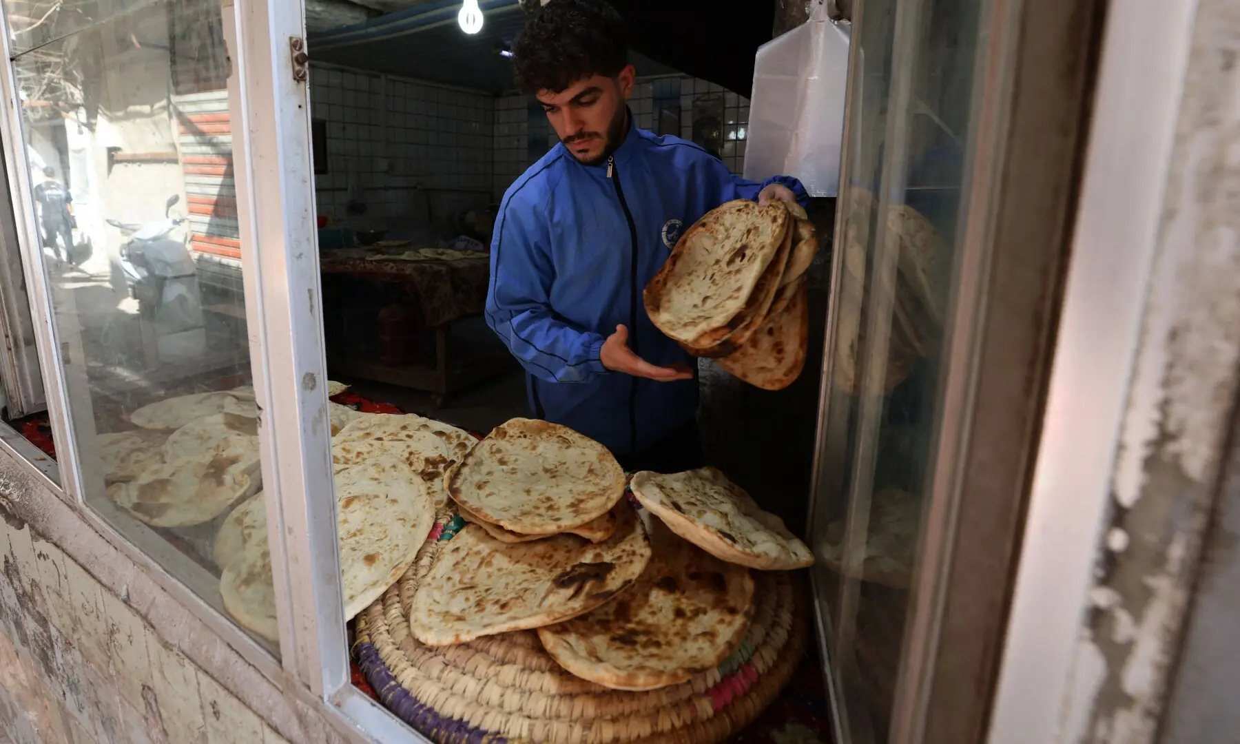 An Iraqi baker takes out the bread from a stone oven in his bakery during the Muslim holy fasting month of Ramazan in Baghdad on February 19, 2026. Muslims throughout the world are marking the month of Ramazan, the holiest month in the Islamic calendar, during which devotees fast from dawn until dusk. &mdash;AFP