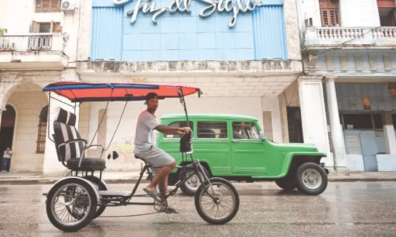 A bicycle taxi and a car drive along a street in Havana as life remains normal despite tensions with US.&mdash;AFP/File