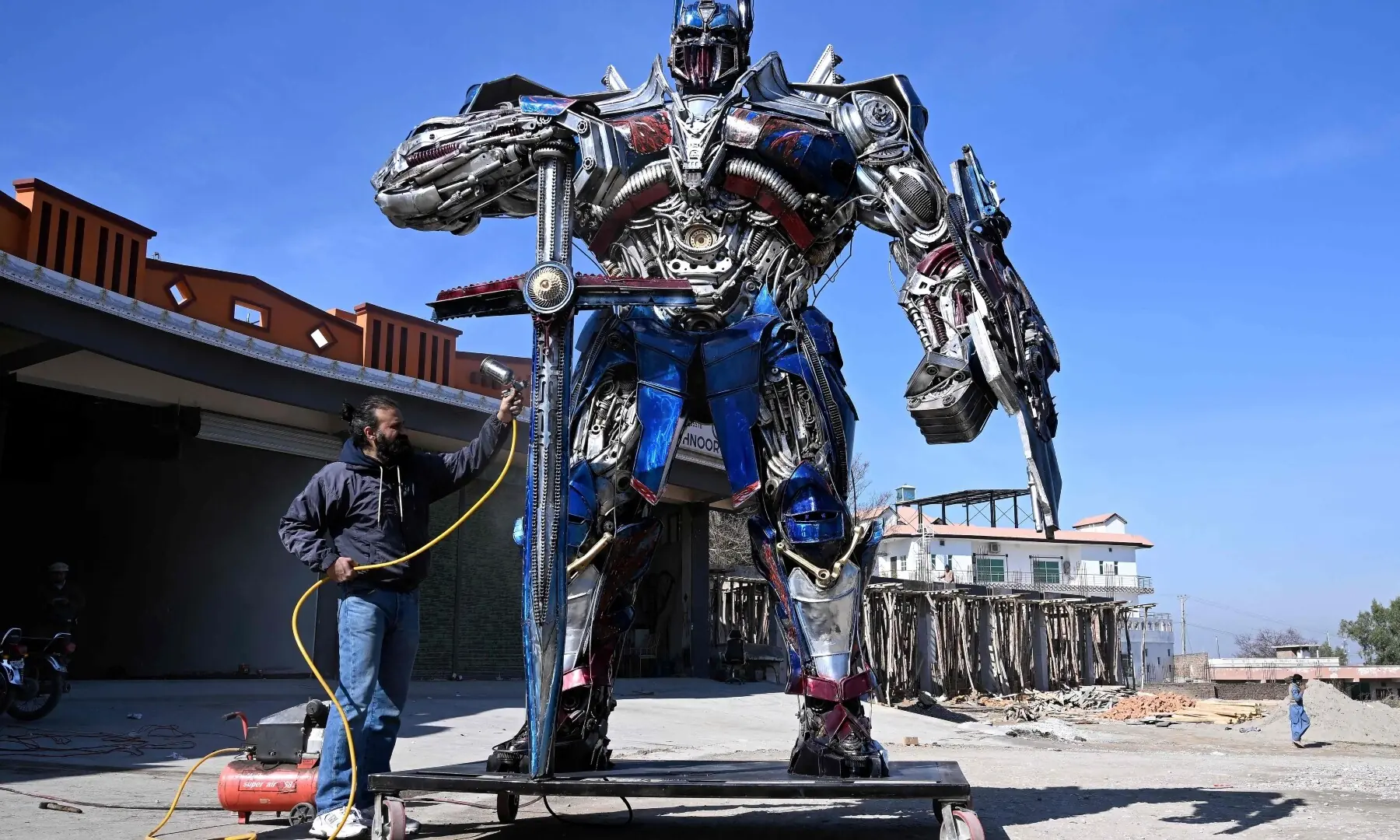 This photograph taken on February 12, 2026 shows sculptor Ehtisham Jadoon working on a model of Optimus Prime, a film character from Transformers, made from scrap metal at his studio on the outskirts of Islamabad. &mdash; AFP